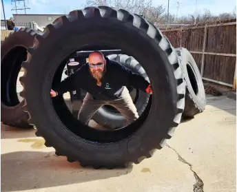 Dax the owner of MrJunk® standing looking through a giant tire ready to be disposed of