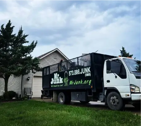 MrJunk® in front of a residential home doing a cleanout parked in the driveway on a cloudy day