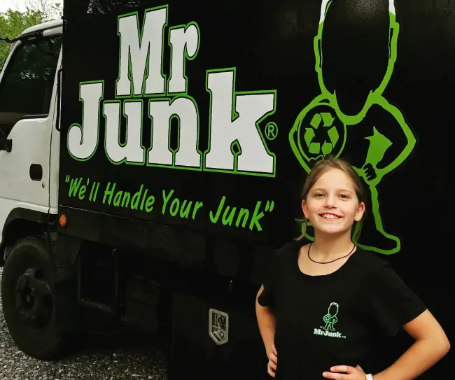 MrJunk® young crew family member Lainy standing in front of the MrJunk® Isuzu workhorse truck